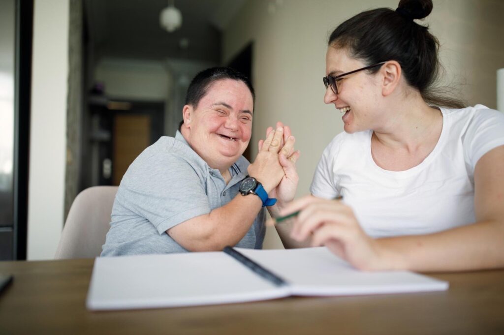 Disabled man high-fiving his in home disability support worker.